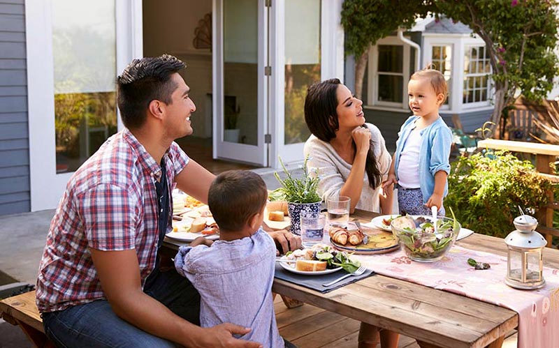 Family eating dinner together outside their new house after a home inspection